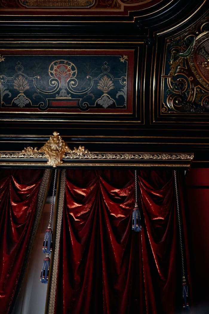 Ornate interior with luxurious red curtains and gilded architectural decor.